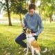 man holding stick in front of dog