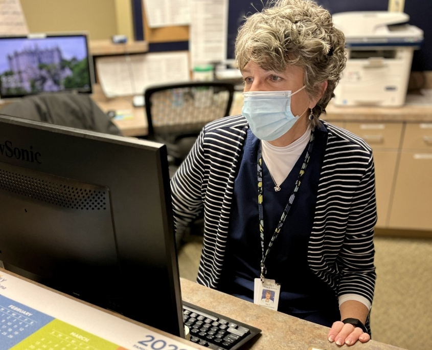 Woman wearing a mask and looking at a computer