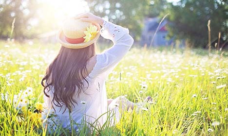 Women laying in field of flowers holding her sun hat free of allergies