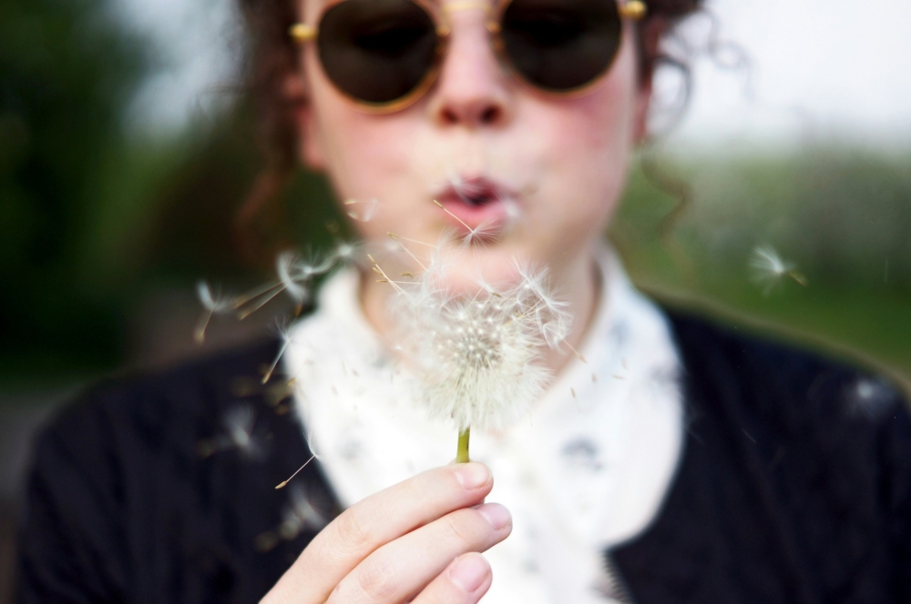 Woman blowing a dandelion.